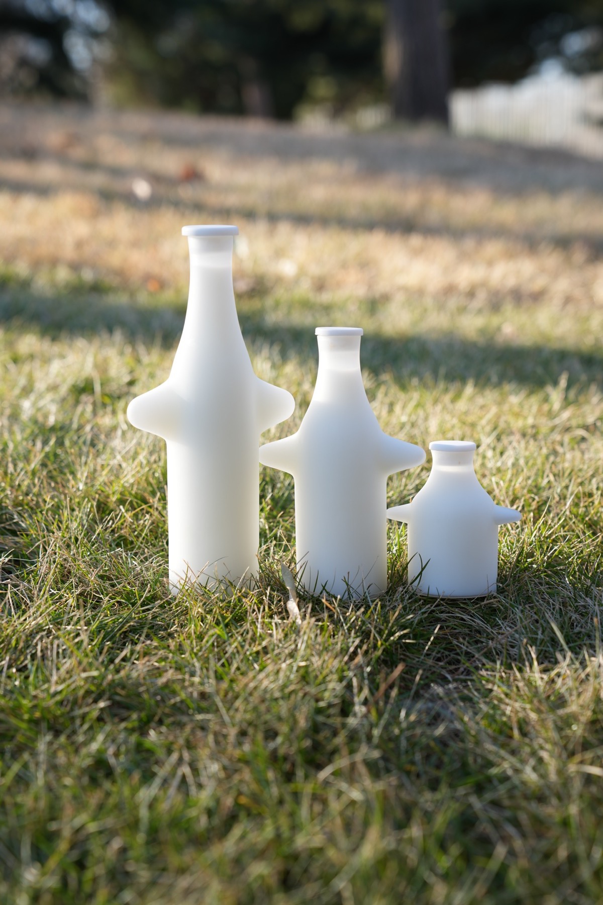 Three white bottles on the grass