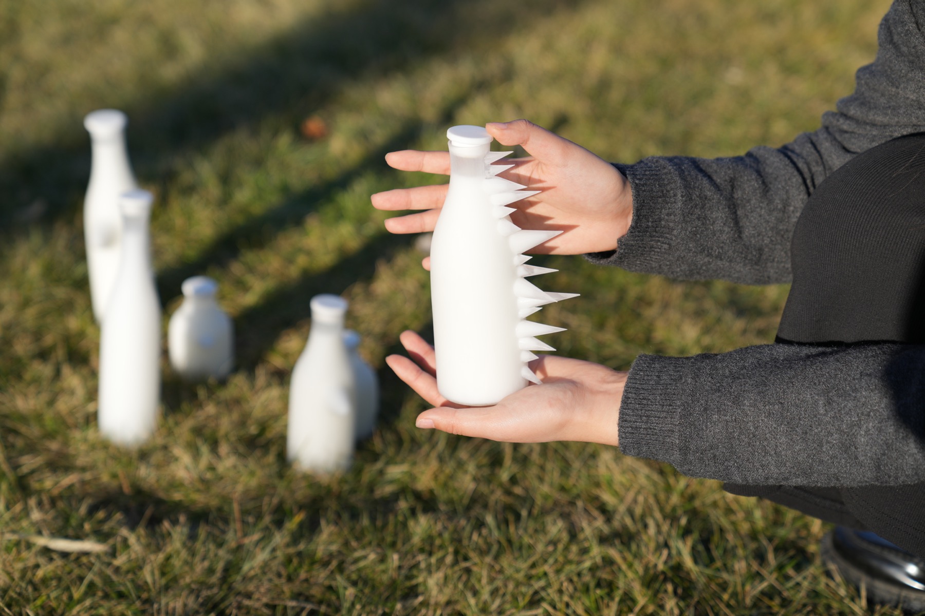 Hands holding a spiked bottle outdoors