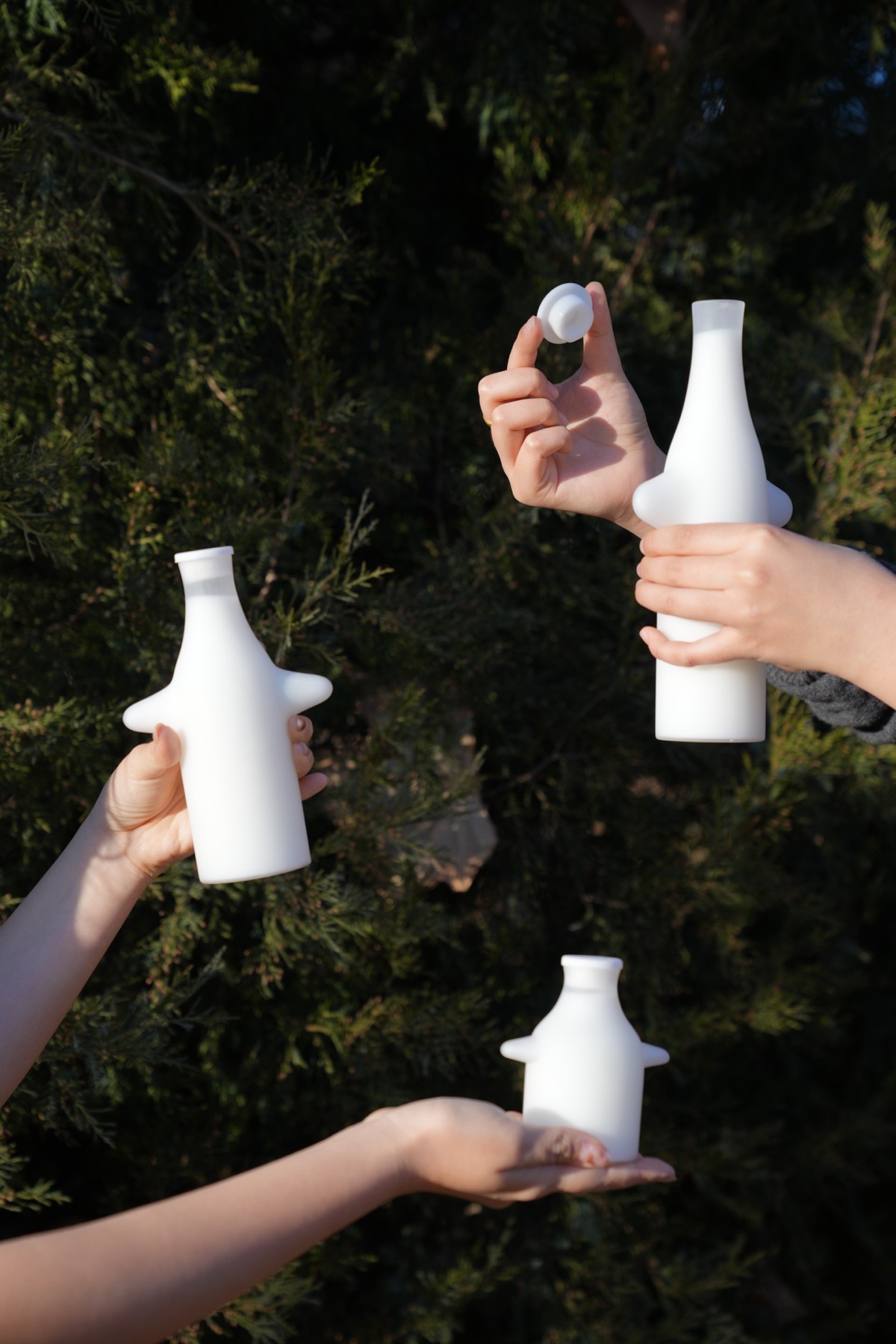 Hands holding three bottles in the garden